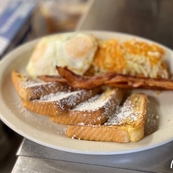 A breakfast plate from Mr T's Family Cafe with French toast, bacon, fried eggs, and hash browns.